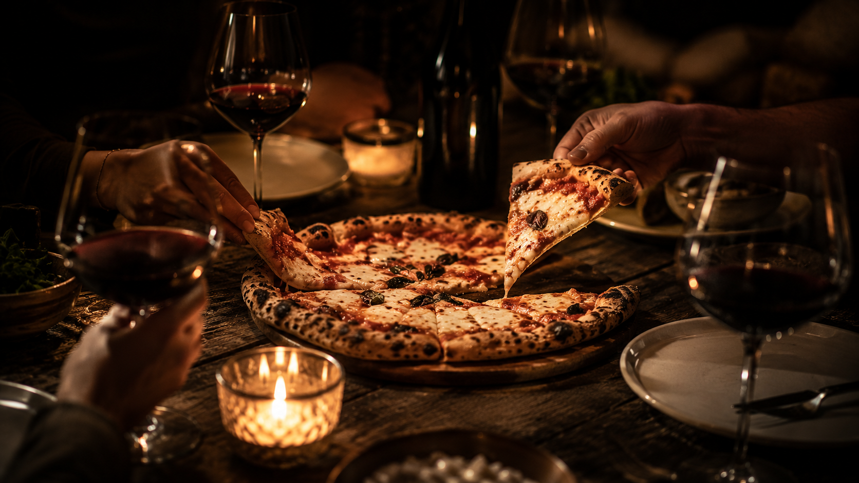 Mesa compartida: pizza artesanal PICACCIA, copas de vino y velas en una sobremesa íntima